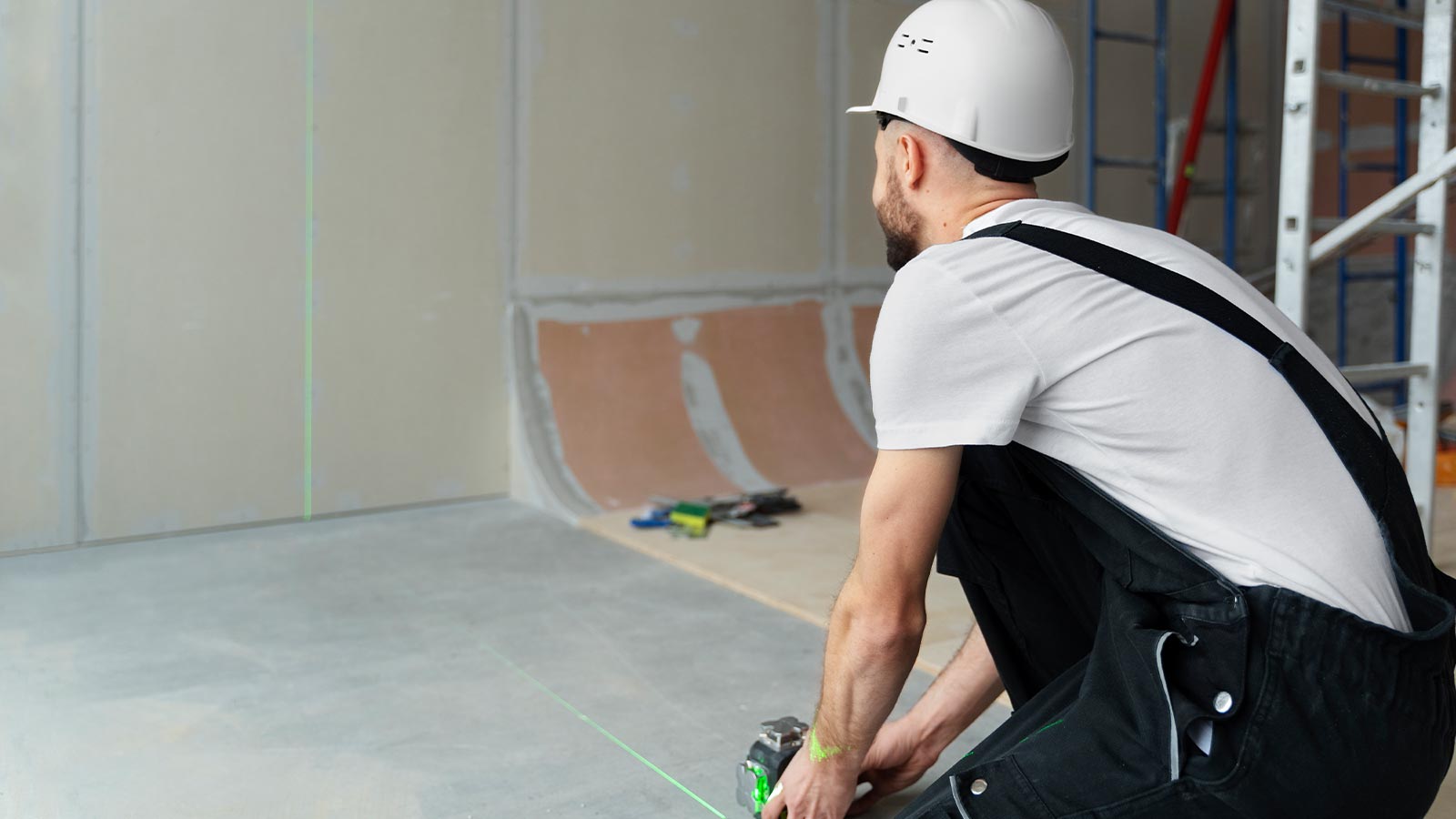 Handwerker richtet mit einem grünen Linienlaser eine Trockenbauwand aus – Baustelle der Sanitec GmbH in Krefeld