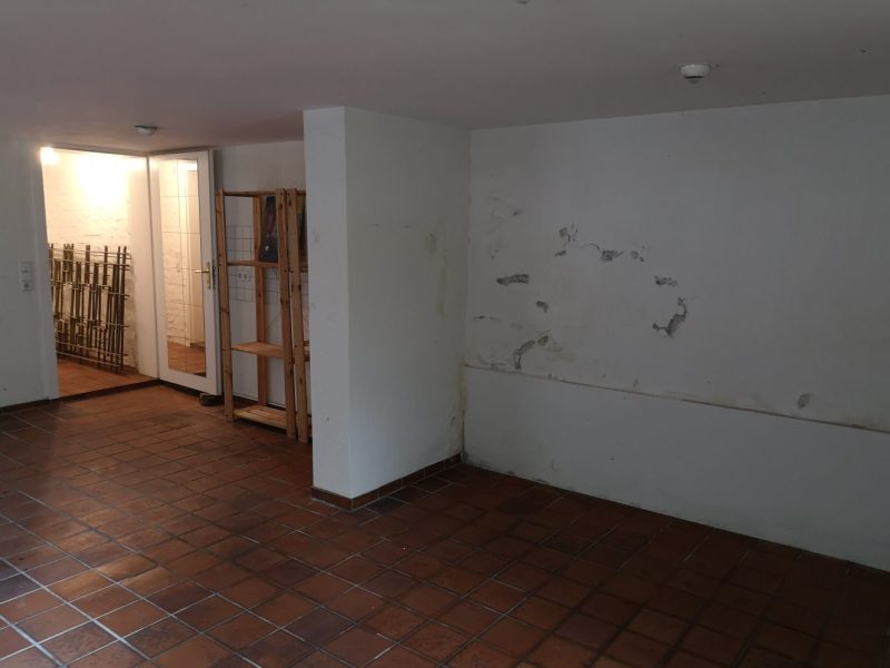 Kellerwand mit abplatzendem Putz und waagerechtem Feuchtigkeitsrand vor der Innenabdichtung