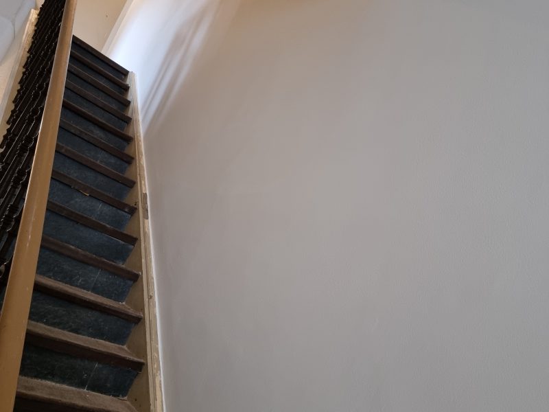 Treppenhaus mit fertig aufgezogenem Sanierputz und glatter heller Wandfläche
